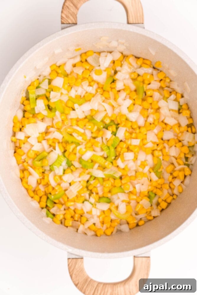 Creamy Corn Chowder 8 Corn and onions gently simmering in a pan, building the foundational flavors for a delicious corn chowder.