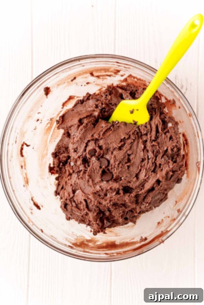 No-Bake Brownie Batter 8 A spatula stirring the thick, rich edible brownie batter in a bowl, showcasing its smooth and creamy texture.