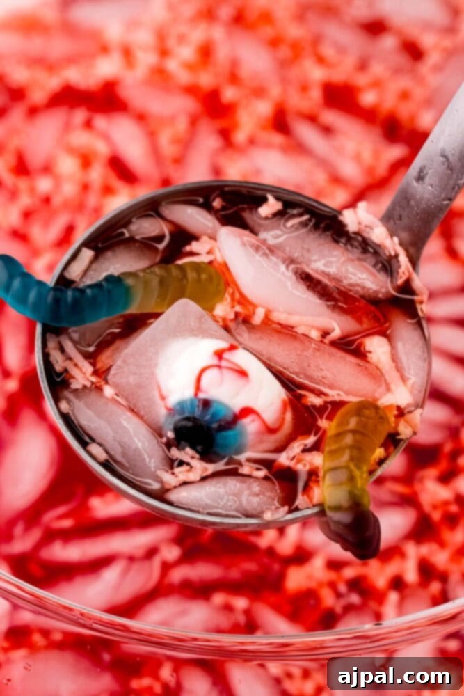 A spoon full of vibrant Halloween fruit punch with a spider candy in it, capturing the spooky essence.