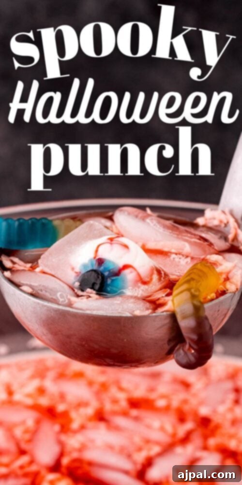 A ladle scooping sparkling Halloween punch, revealing gummy worms and candy eyeballs, ready for a serving.
