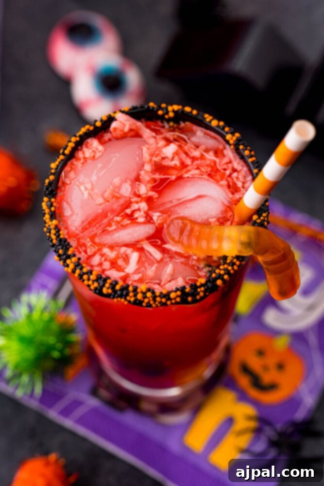 A sparkling Halloween fruit punch served in a glass with festive decorations and a colorful straw, ready for a party.