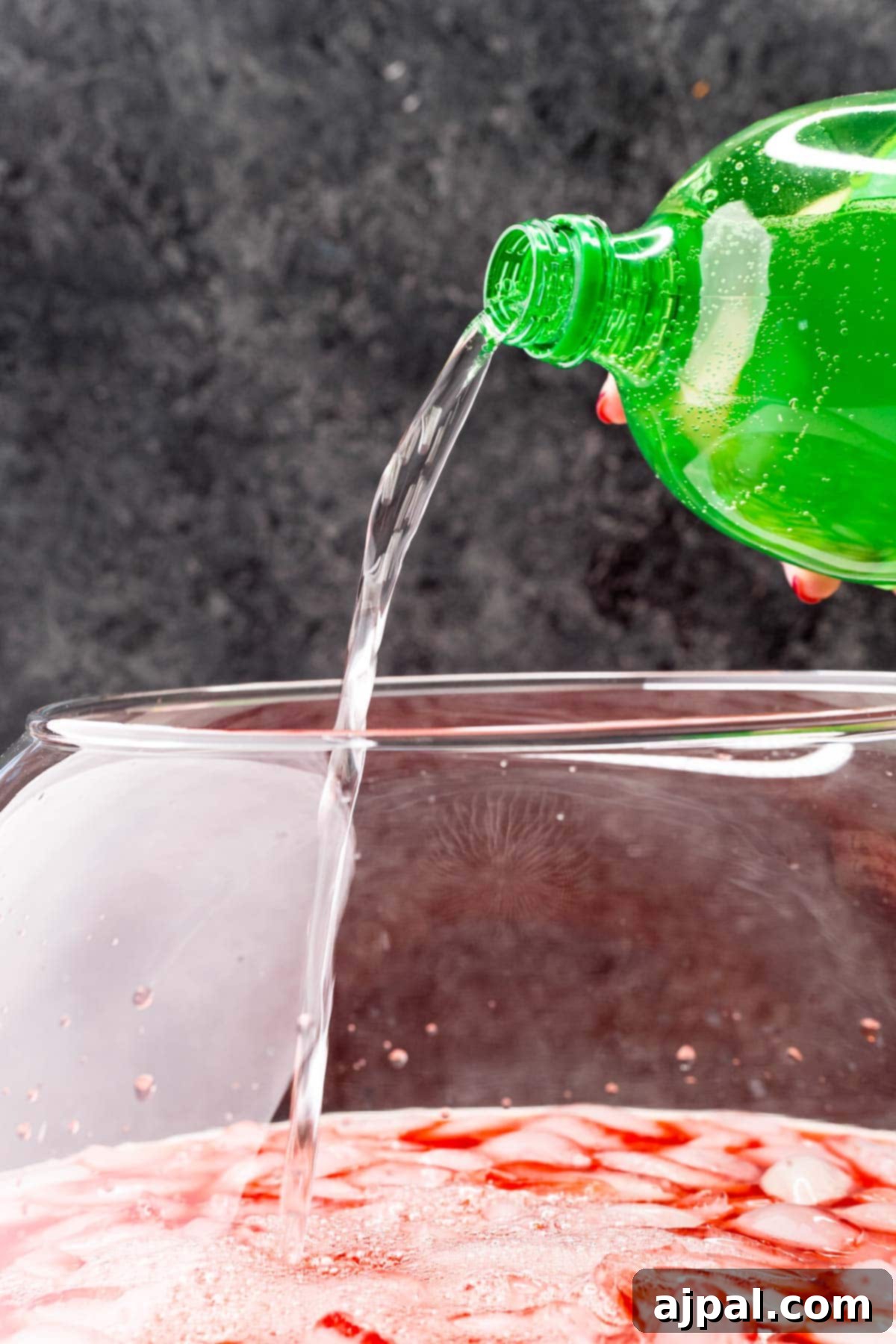 A picture of lemon-lime soda being carefully poured into a large punch bowl filled with ice.