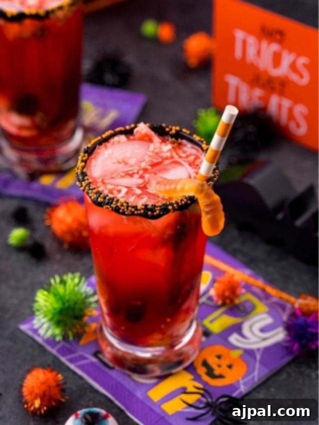 A festive Halloween punch with gummy worms and themed decorations set on a table for a party.