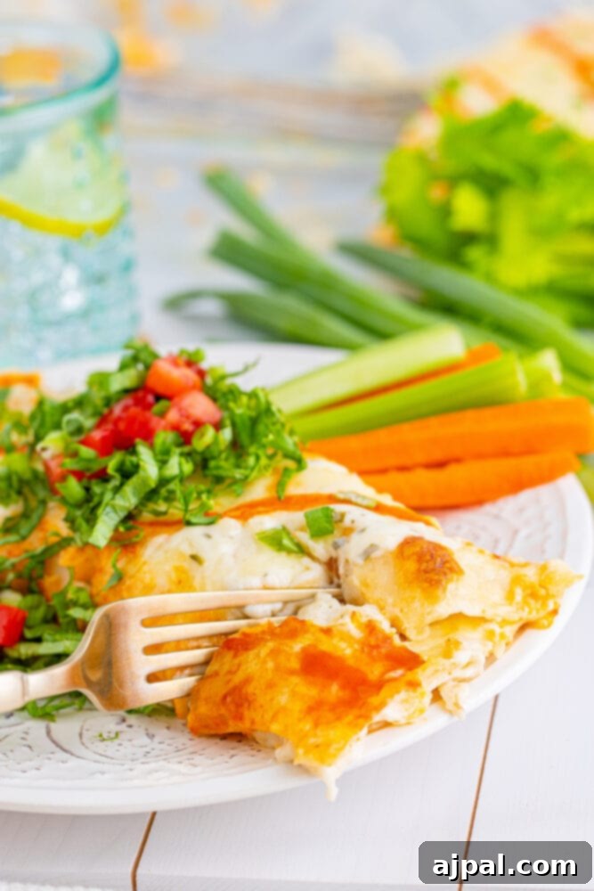 A delicious serving of Buffalo Ranch Chicken Enchiladas, complete with a fork, ready for a satisfying meal.