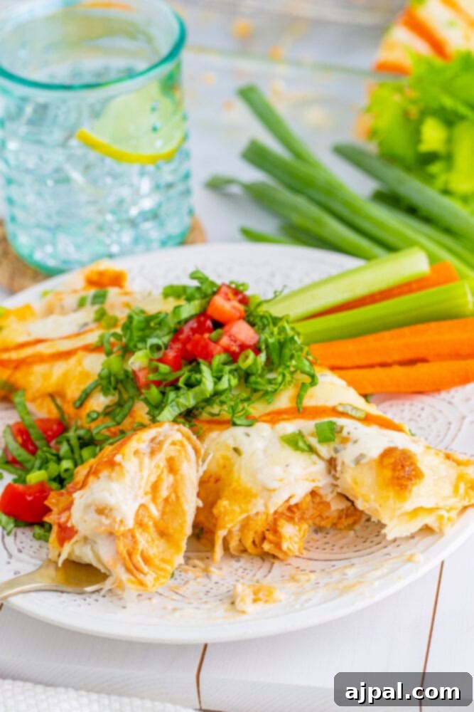 Close-up of baked Buffalo Ranch Chicken Enchiladas, golden and bubbly from the oven.