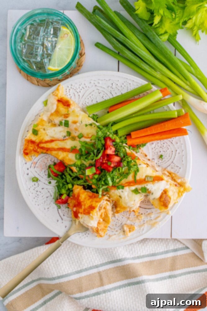 A plate of Buffalo Ranch Chicken Enchiladas garnished with fresh celery and carrot sticks, embodying the classic buffalo wing accompaniment.