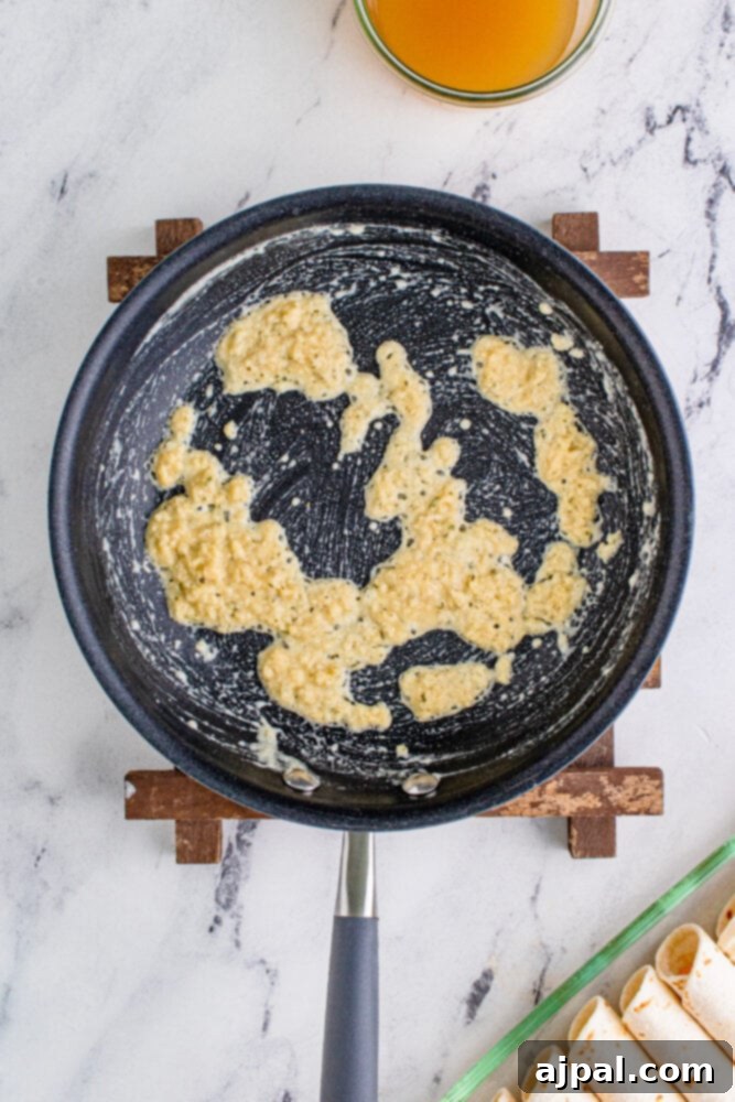A creamy, thickened ranch sauce simmering gently in a pan, ready to be poured over the enchiladas.