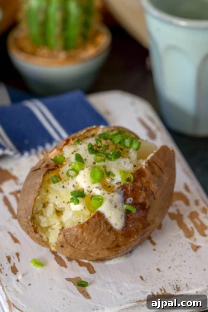 An air fryer potato recipe yielding a delicious baked potato on a wooden cutting board.