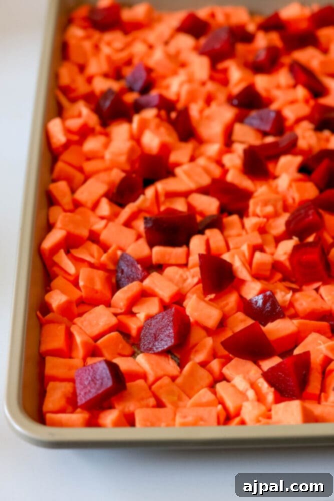 Effortless Roasted Beets & Sweet Potatoes 4 picture of raw sweet potato and beet cubes on a baking sheet