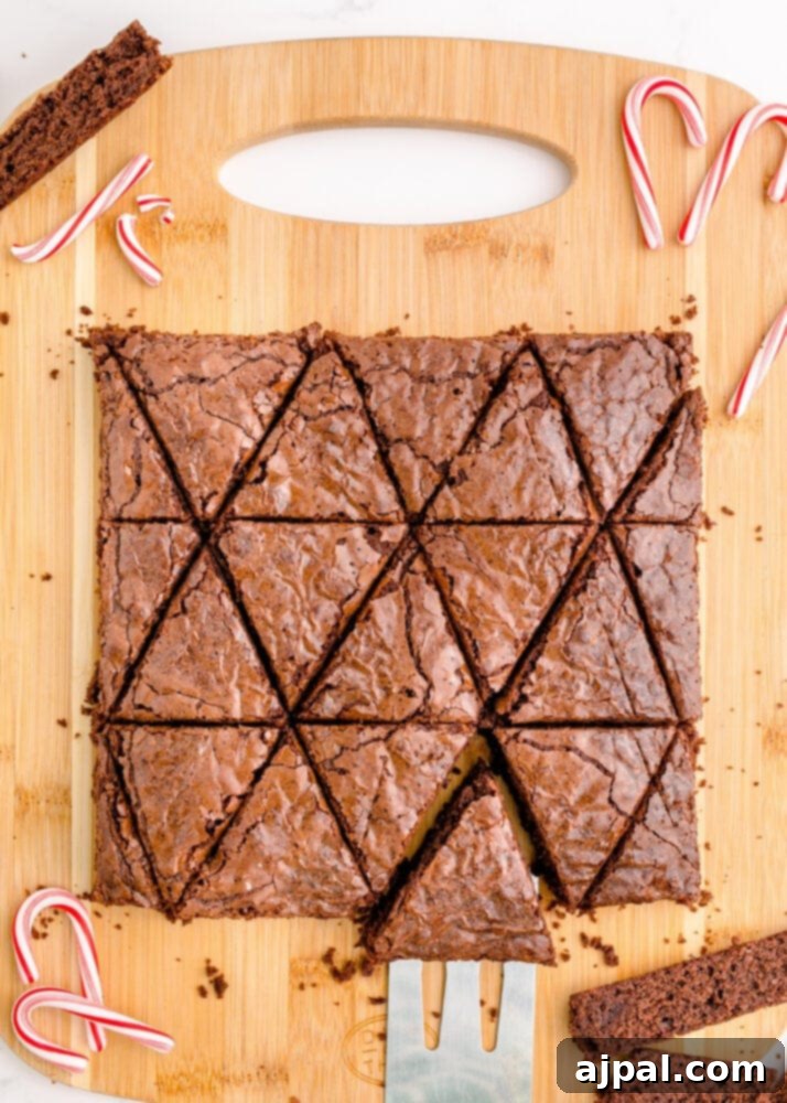 Festive Fudgy Evergreen Brownies 12 Triangular brownie pieces carefully arranged on a cutting board, demonstrating the various Christmas tree shapes created from the original brownie slab.