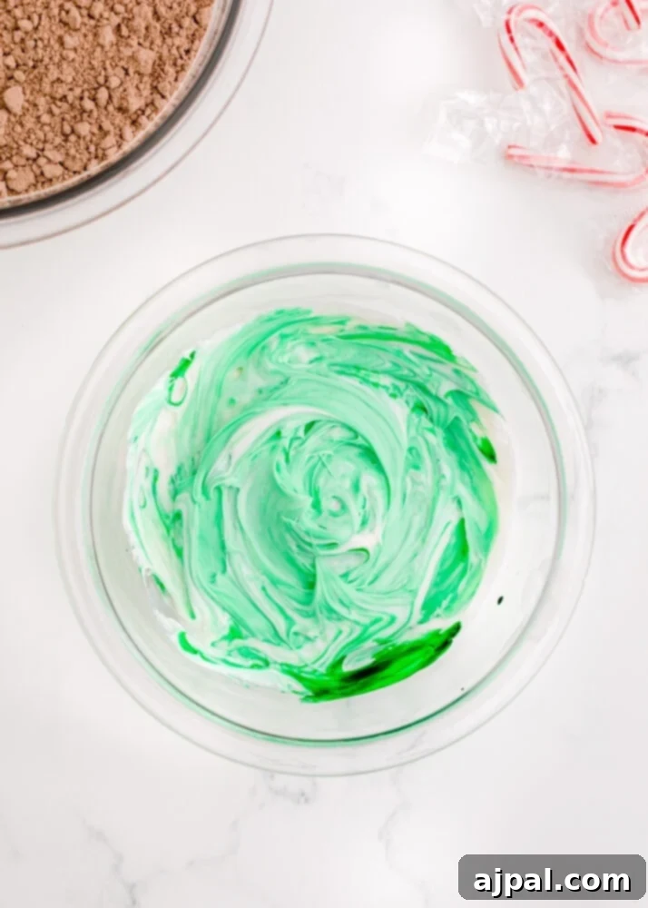 Festive Fudgy Evergreen Brownies 15 A spatula stirring green food coloring into white frosting, showing the color beginning to spread and blend.