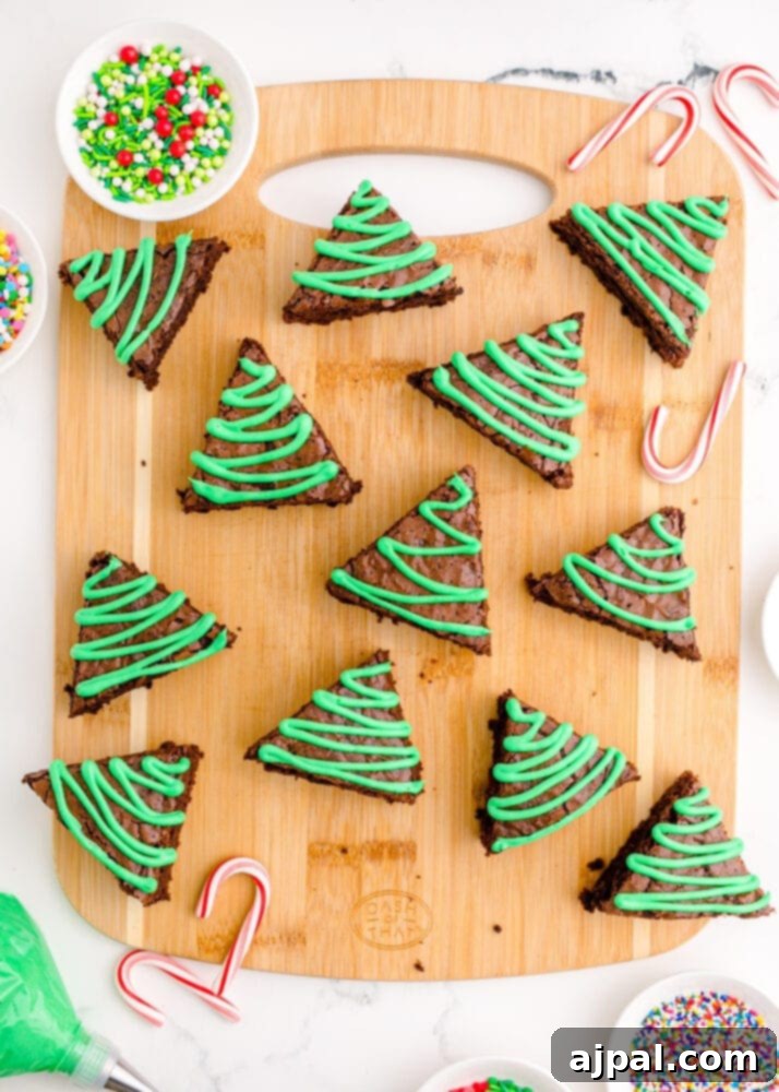 Festive Fudgy Evergreen Brownies 18 A fully frosted brownie triangle resembling a Christmas tree, with green icing piped on top, ready for sprinkles.