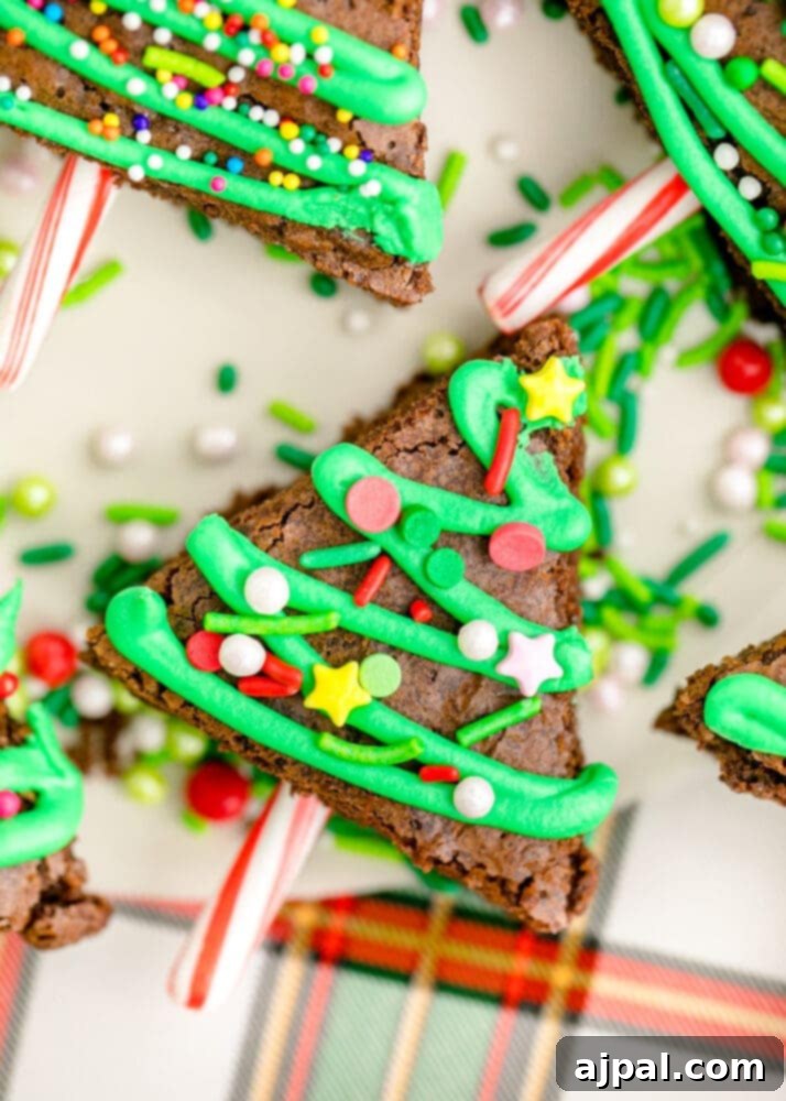 Festive Fudgy Evergreen Brownies 21 A close-up of a festive Christmas tree brownie, richly iced and adorned with sprinkles, and a candy cane trunk.