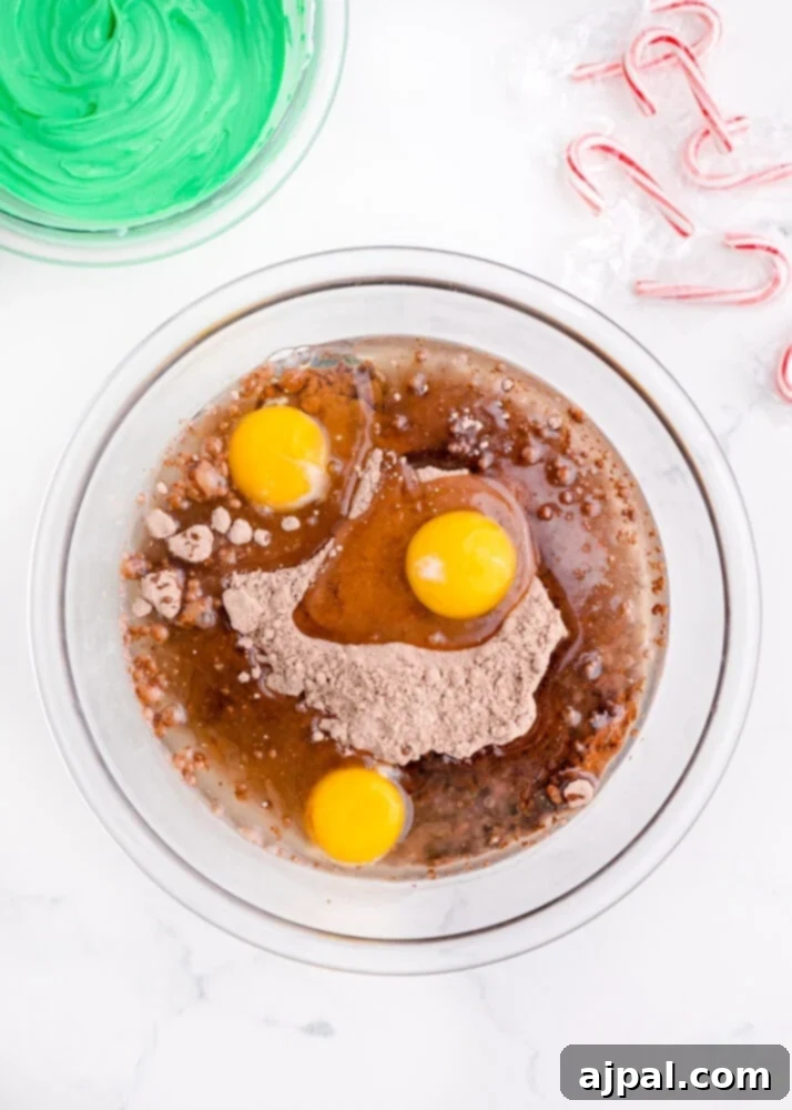 Festive Fudgy Evergreen Brownies 5 Brownie ingredients, including the mix, oil, and eggs, combined in a large mixing bowl.