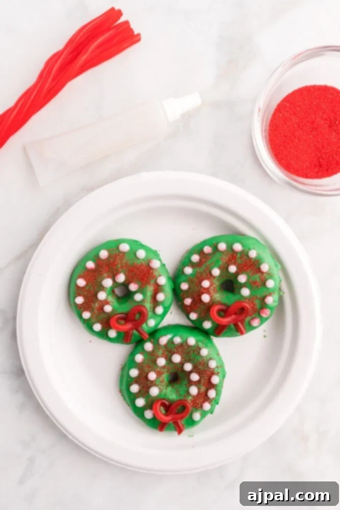 Effortless Christmas Wreath Cookies 11 A festive green Christmas wreath cookie, elegantly embellished with delicate red glitter gel lines and an assortment of sparkling gold and white beads.