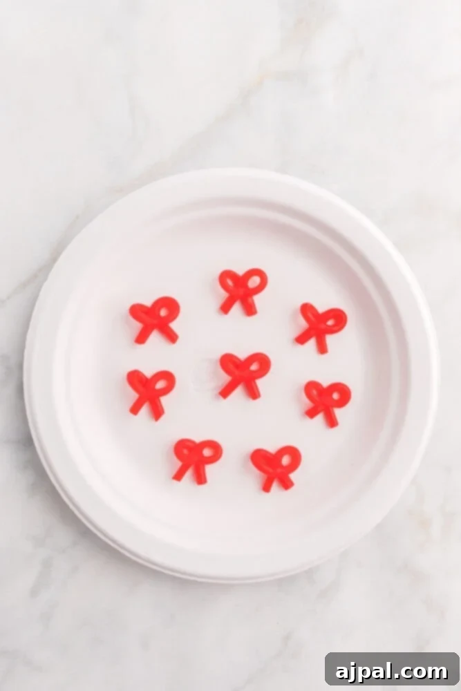Effortless Christmas Wreath Cookies 8 A pristine white plate adorned with charming red licorice bows, thoughtfully arranged next to a selection of freshly dipped Easy Christmas Wreath Cookies.