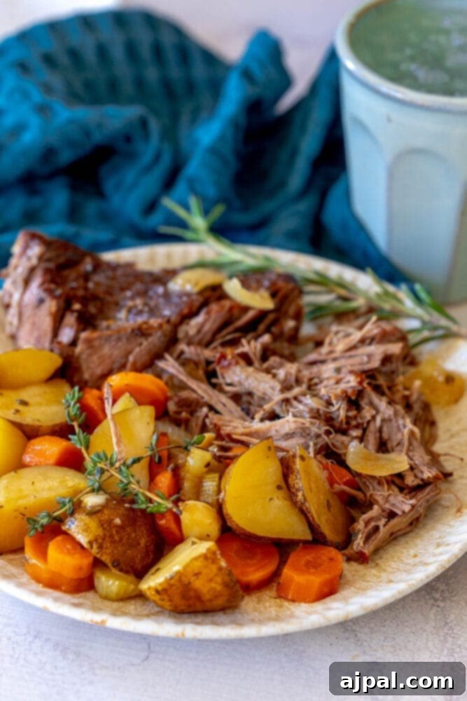 Ultimate Comfort Pot Roast with Tender Potatoes 12 Shredded pot roast, potatoes, carrots, and fresh thyme on a plate, ready to be enjoyed.