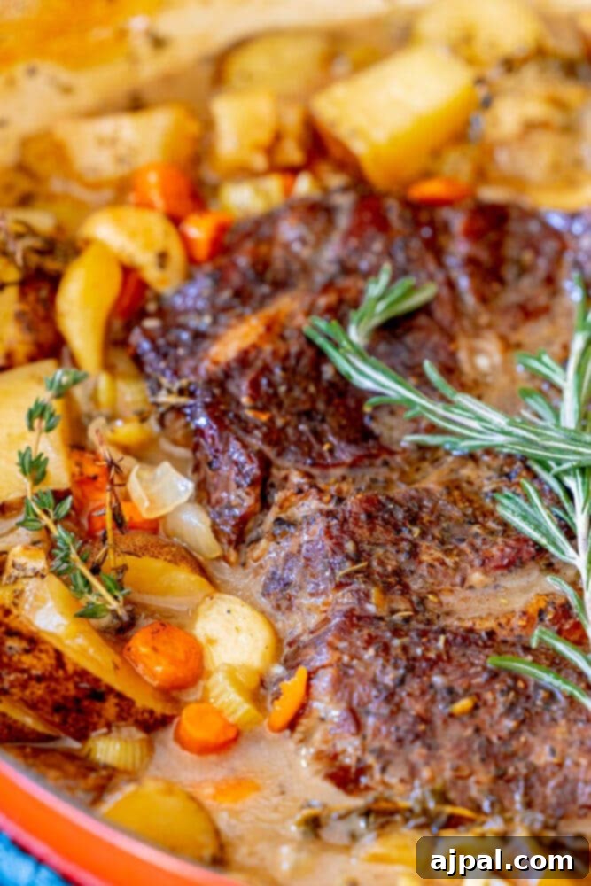 Ultimate Comfort Pot Roast with Tender Potatoes 13 Pot roast in a Dutch oven with vegetables and rosemary on top, ready to be served.