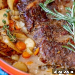 pot roast in a dutch oven with vegetables and rosemary on top