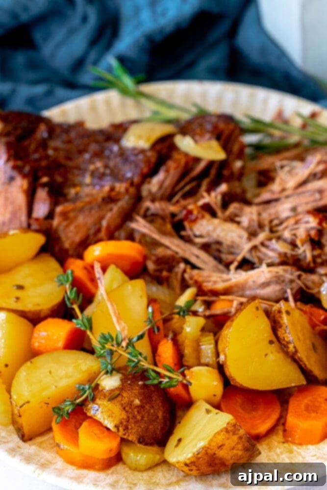 Ultimate Comfort Pot Roast with Tender Potatoes 3 Shredded pot roast, potatoes, carrots, and fresh thyme beautifully arranged on a plate.