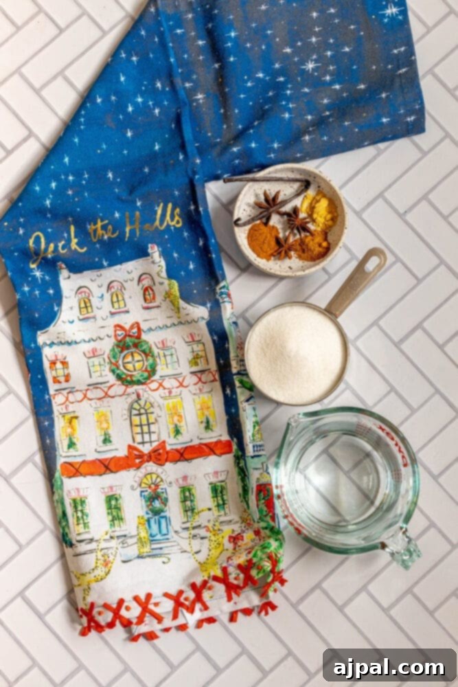 Warming Winter Spice Syrup 5 A tea towel with a Christmas house and spices, including mulling spice simple syrup.