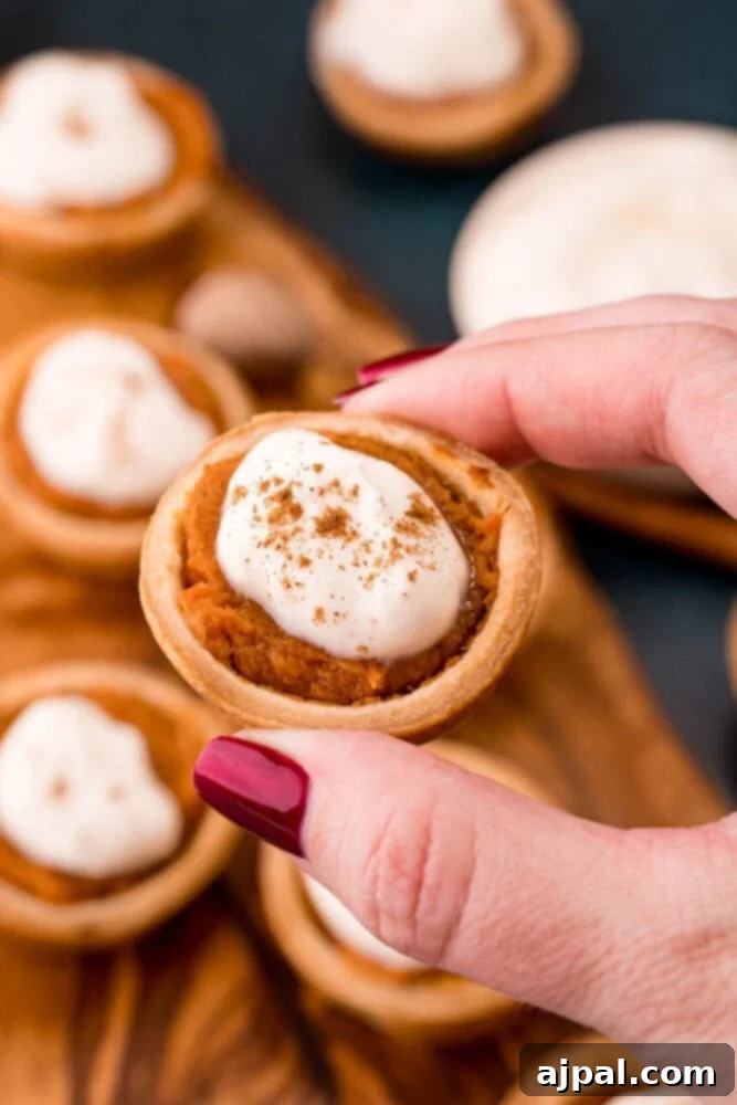 Exquisite mini sweet potato pies, perfectly baked and garnished with whipped cream, artfully arranged on a rustic wooden cutting board, inviting a delightful tasting experience.