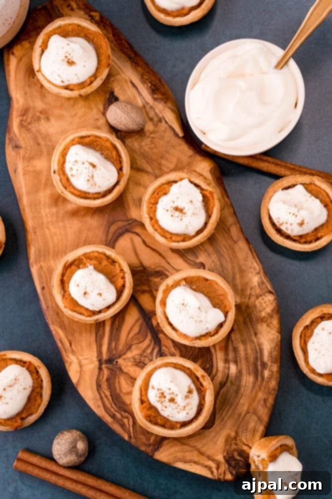 A collection of delectable sweet potato pies, elegantly topped with whipped cream and garnished with delicate cinnamon sticks, all presented on a rustic wooden board.