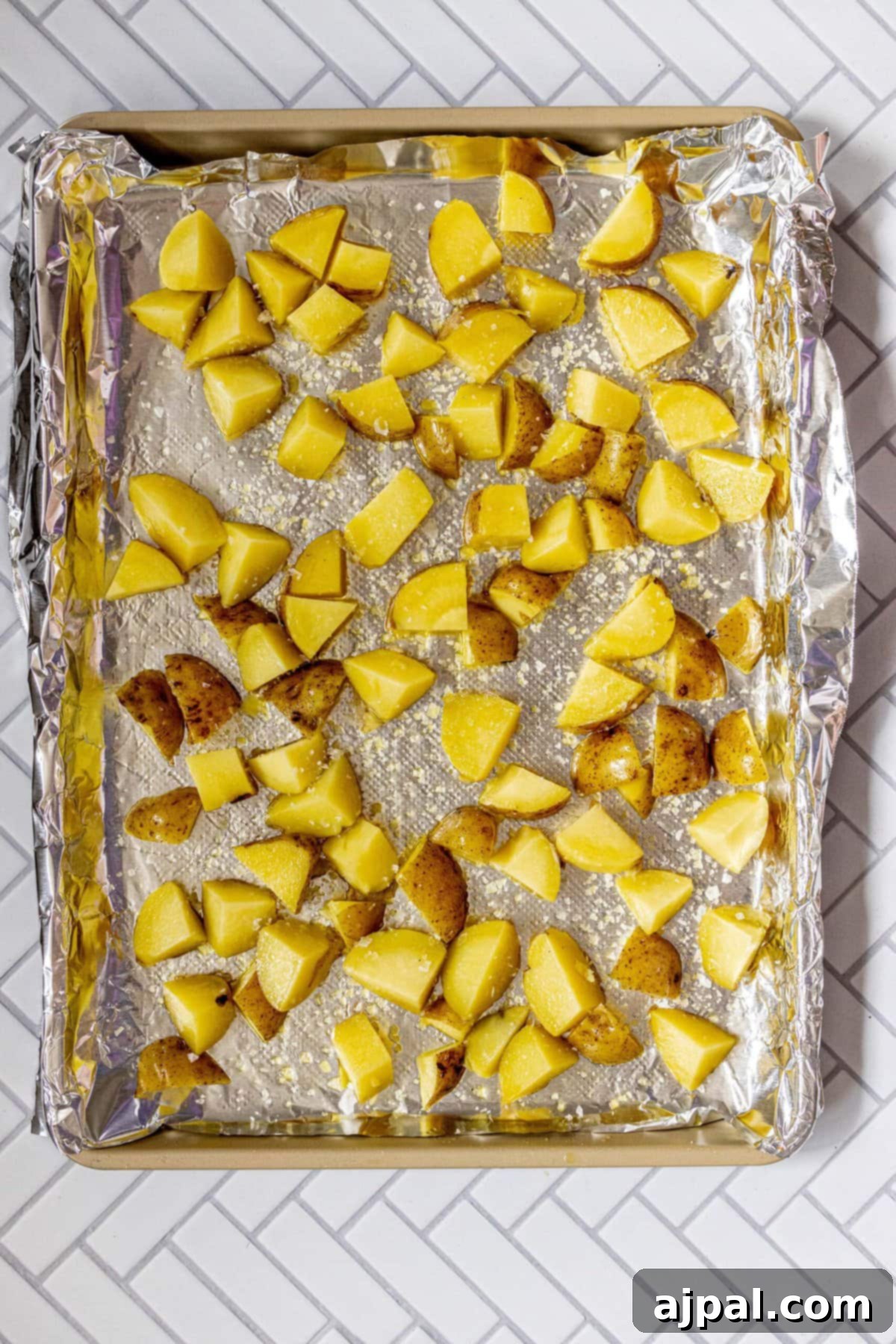 Tossing potatoes with seasoning on a baking sheet.