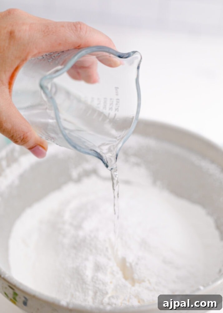 Snowman Meltdown Cookies 14 picture of water being poured into a bowl of powdered sugar for royal icing