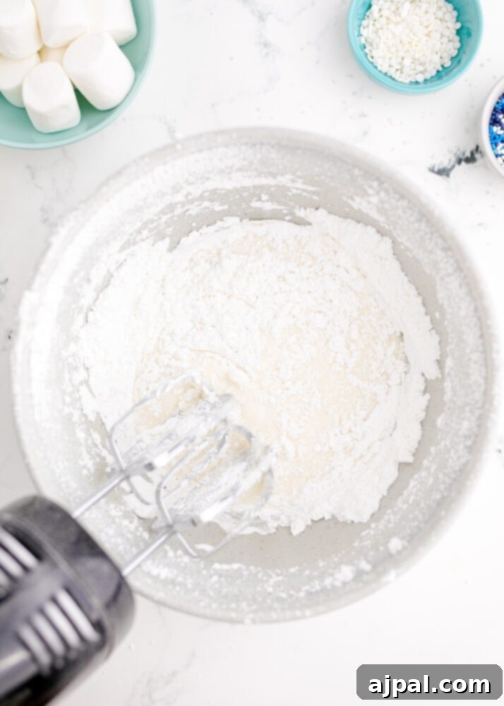 Snowman Meltdown Cookies 15 picture of a mixer in a bowl of powdered sugar and meringue, creating smooth royal icing