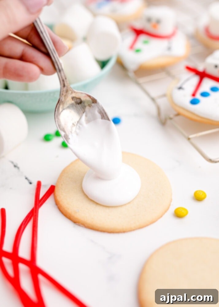 Snowman Meltdown Cookies 18 picture of a spoon putting white icing on a cookie, creating the melted snow base