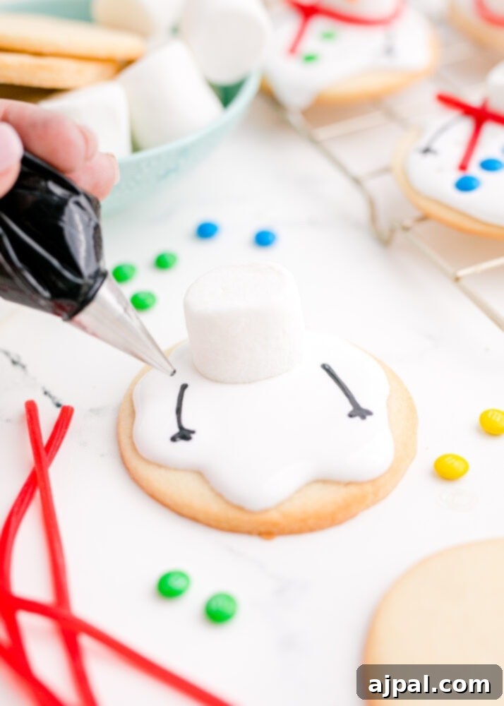 Snowman Meltdown Cookies 21 picture of hand piping black icing arms onto snowman cookie