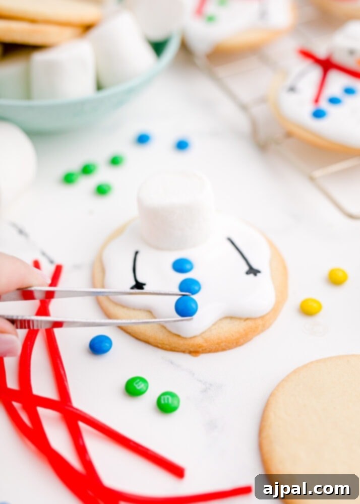 Snowman Meltdown Cookies 22 picture of tweezers placing candy on cookie, meticulously decorating the snowman