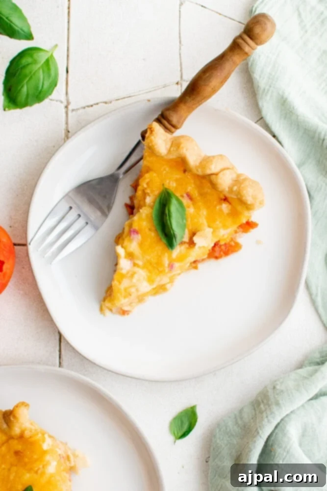 Simple Savory Tomato Pie 20 A tempting slice of baked tomato pie, adorned with fresh basil, artfully presented on a plate.