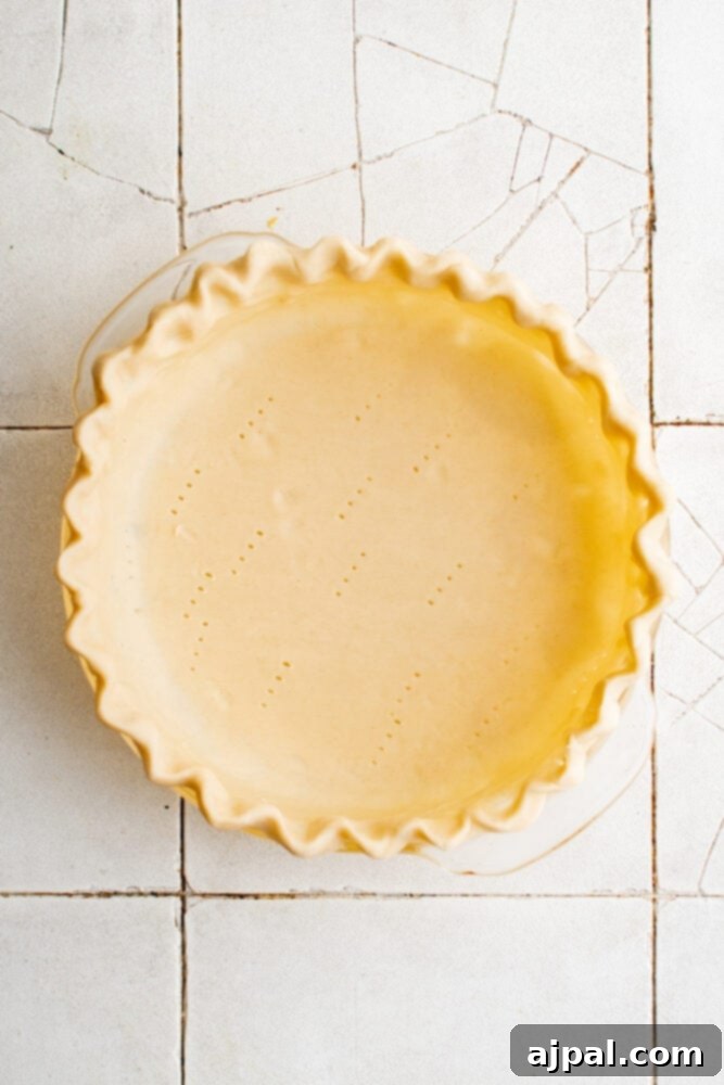 Simple Savory Tomato Pie 7 A raw pie crust expertly pressed into a pie pan with crimped edges, ready for blind baking.