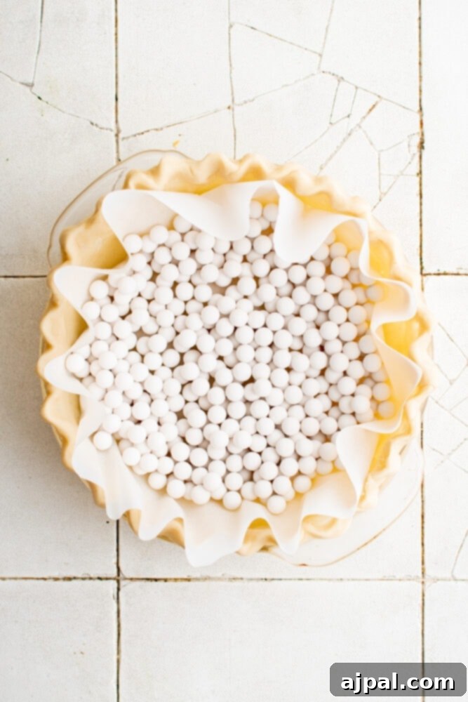 Simple Savory Tomato Pie 8 A pie crust lined with parchment paper and filled with ceramic pie weights, ready for blind baking.