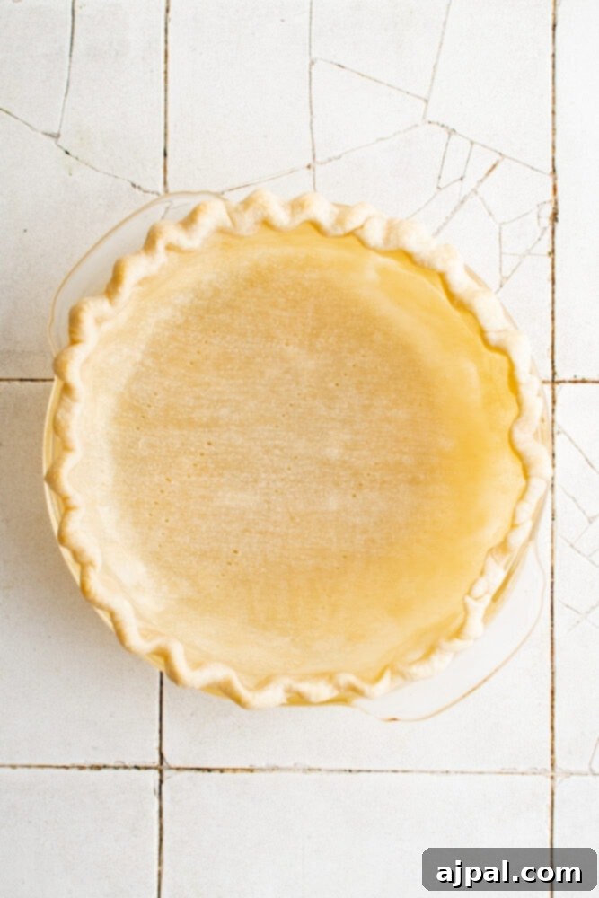 Simple Savory Tomato Pie 9 A golden-brown, blind-baked pie crust in a pie plate, perfectly prepared for filling.