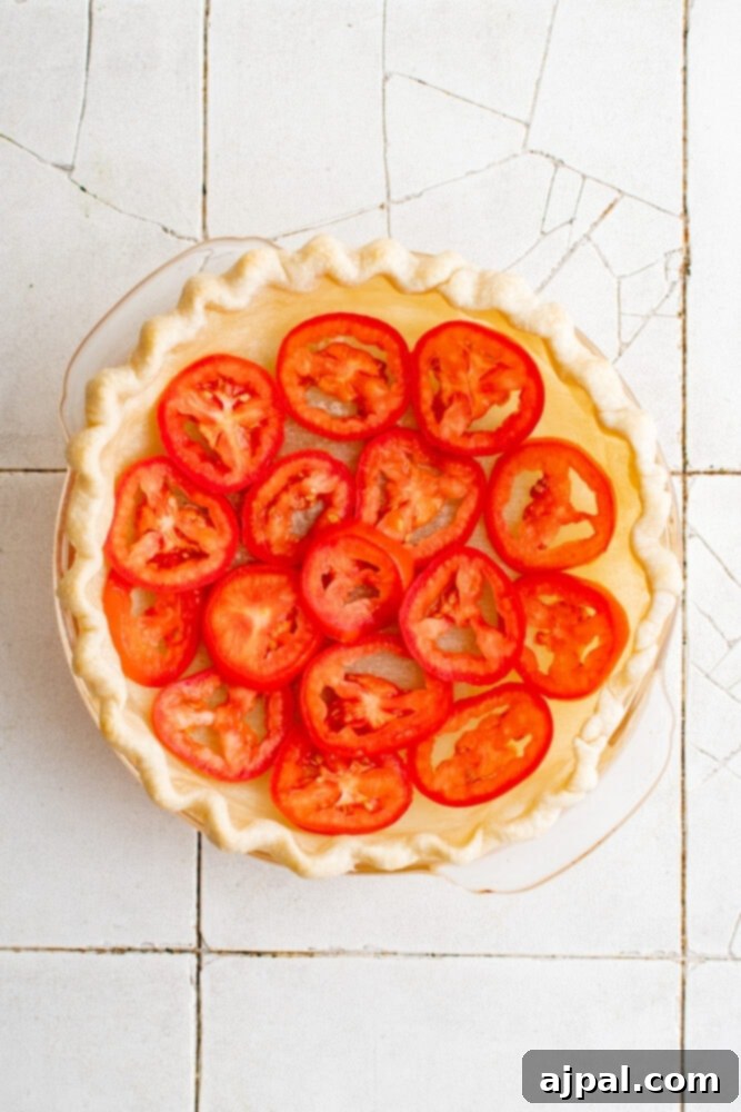 Simple Savory Tomato Pie 10 The first layer of fresh tomato slices arranged neatly within the blind-baked pie crust.