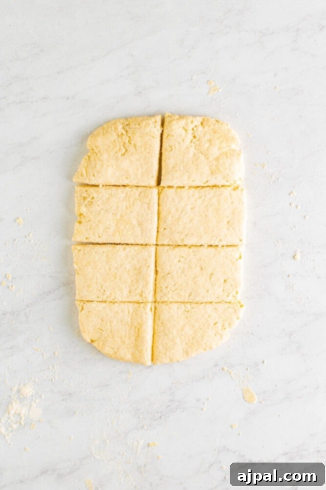 The rolled-out biscuit dough cut into eight even rectangular pieces, ready for placement.