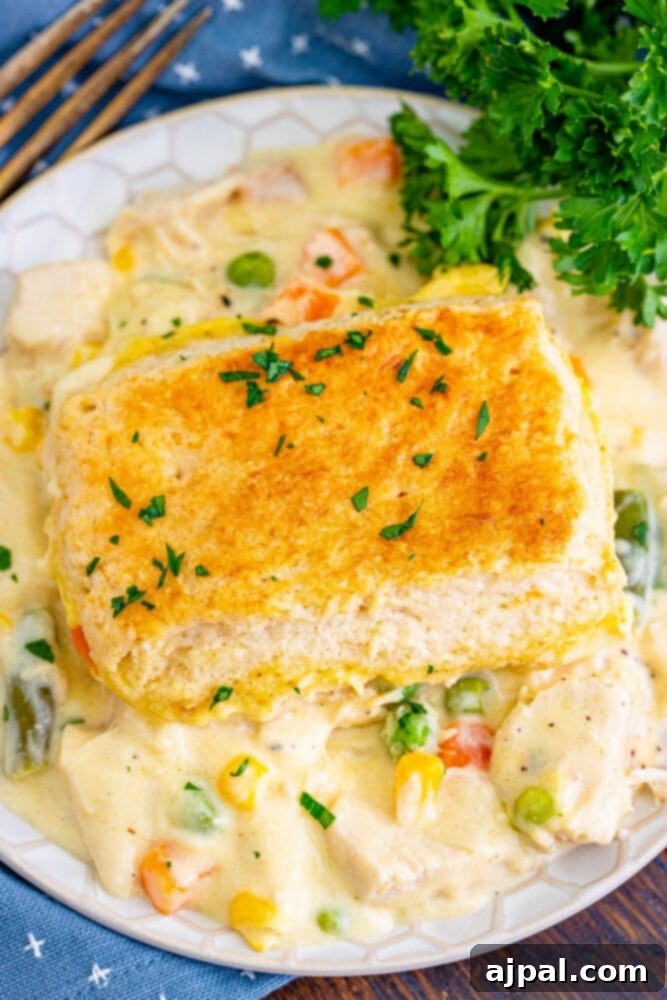A serving of turkey pot pie on a white plate, with a fork poised to take a bite.