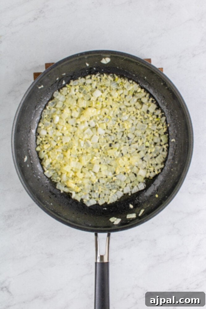 Sliced onions sizzling in melted butter in a pan on a stovetop.