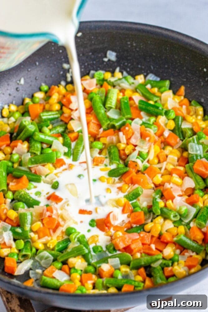 Half and half being poured into a pan with cooked vegetables, creating a creamy base.