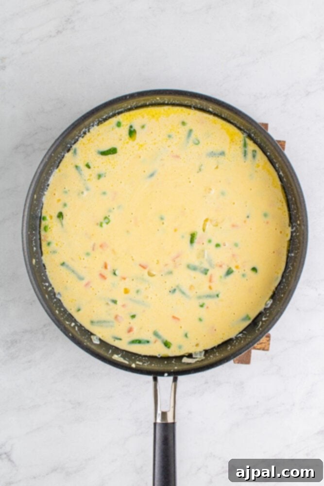 The creamy pot pie filling in a pan, with all ingredients mixed, simmering gently.