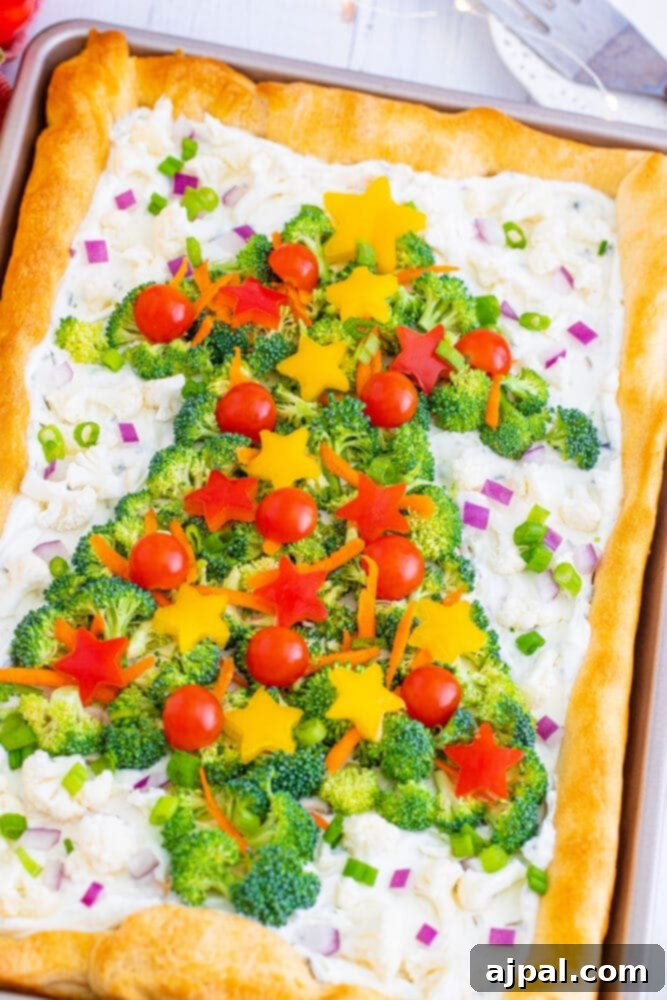 A beautifully arranged vegetable pizza shaped like a Christmas tree, adorned with colorful broccoli florets, cherry tomatoes, and bell pepper stars, resting on a wooden serving board.