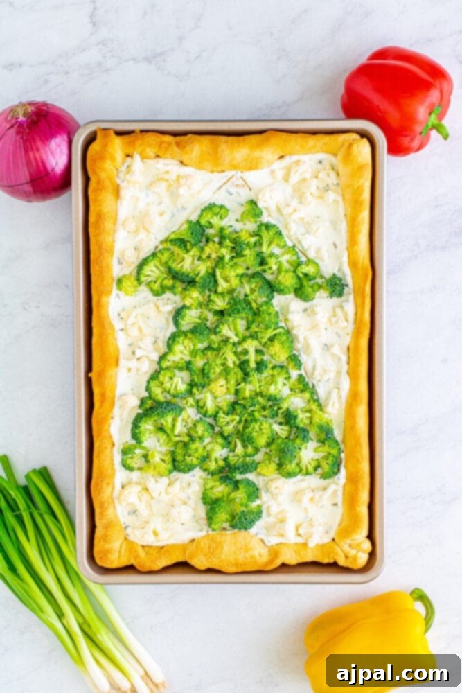 Broccoli and finely diced red onions are arranged to form the early stages of a Christmas tree on the creamy base.