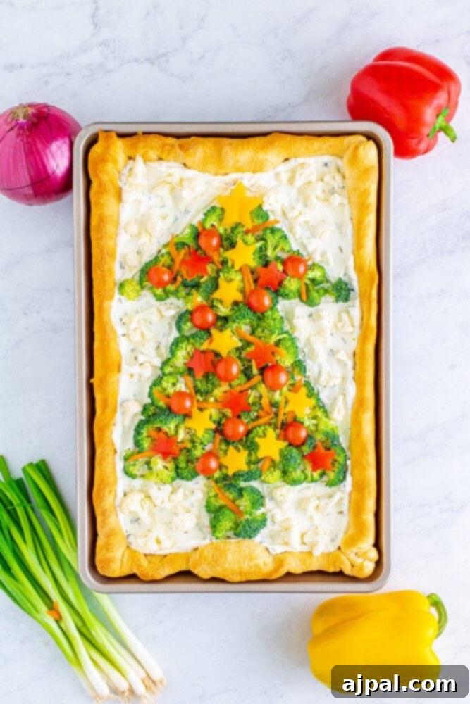 Cherry tomatoes are added as festive 'ornaments' to the broccoli, onion, and carrot Christmas tree pizza.