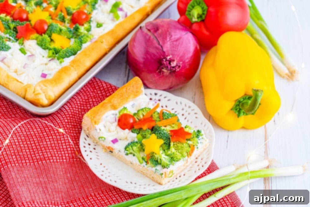 A perfectly sliced piece of Christmas tree vegetable pizza, showcasing its flaky crust, creamy base, and colorful toppings on a white plate.