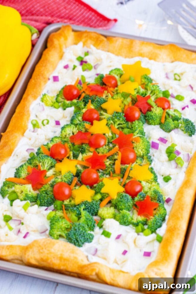 A festive vegetable Christmas tree pizza, richly topped with broccoli, vibrant red and yellow peppers, and carrots, ready to be served.