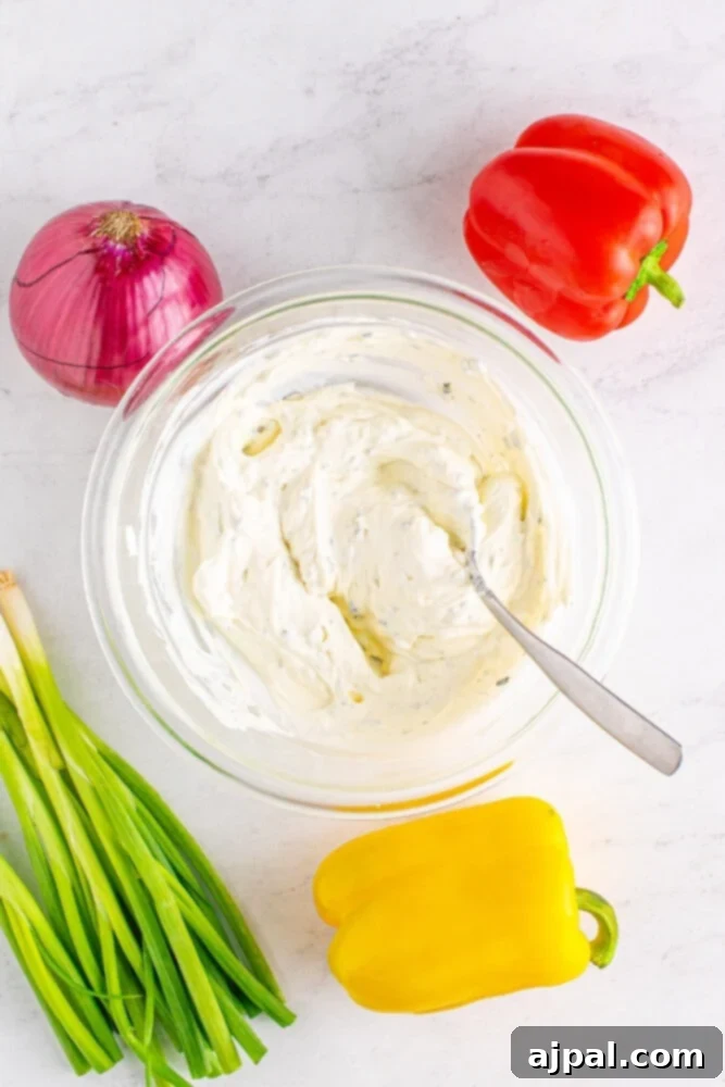 A bowl holding a smooth, combined mixture of chive cream cheese and sour cream, creating a luscious base for the vegetable pizza.