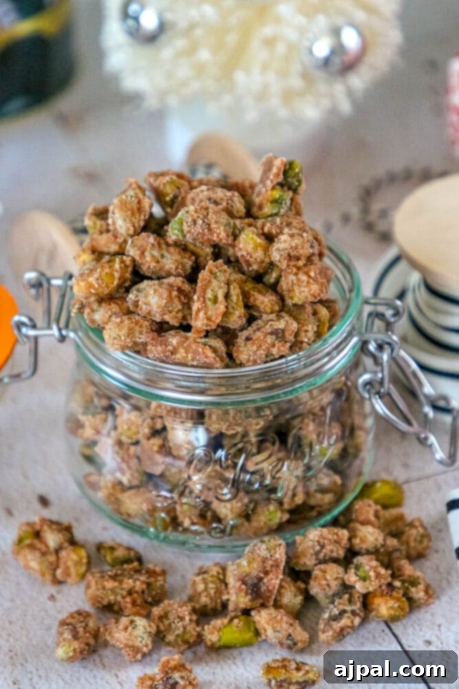 Close-up of golden-brown candied pistachios in a clear glass jar, showcasing their sweet, spiced coating and vibrant green color.